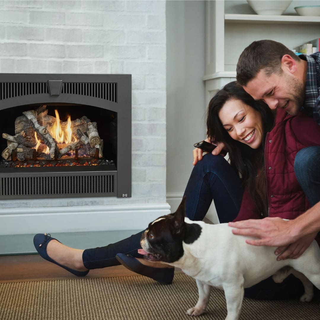 couple laughing with dog in front of fireplace